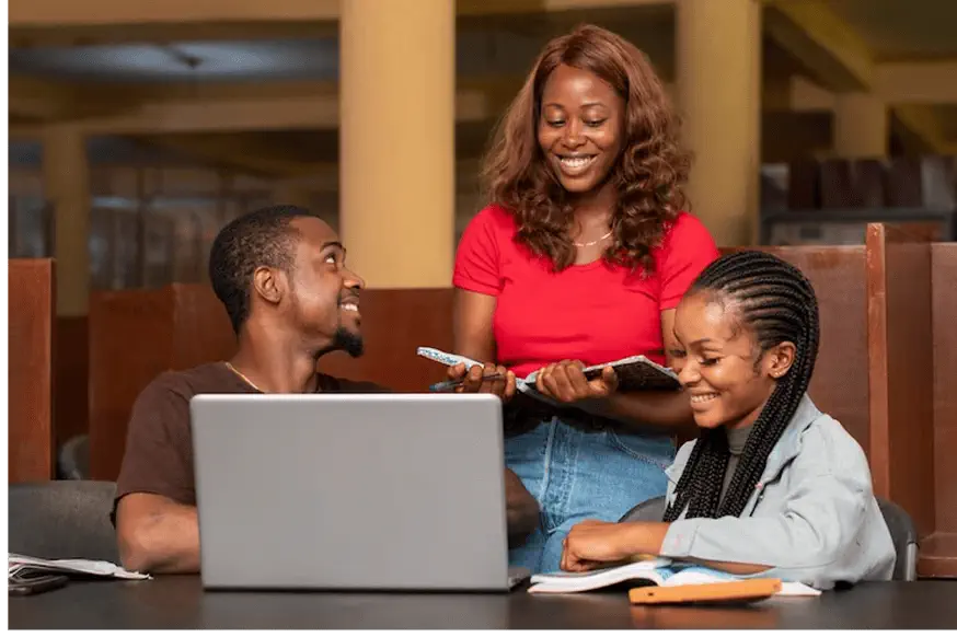  a group of people sitting around a table with a laptop